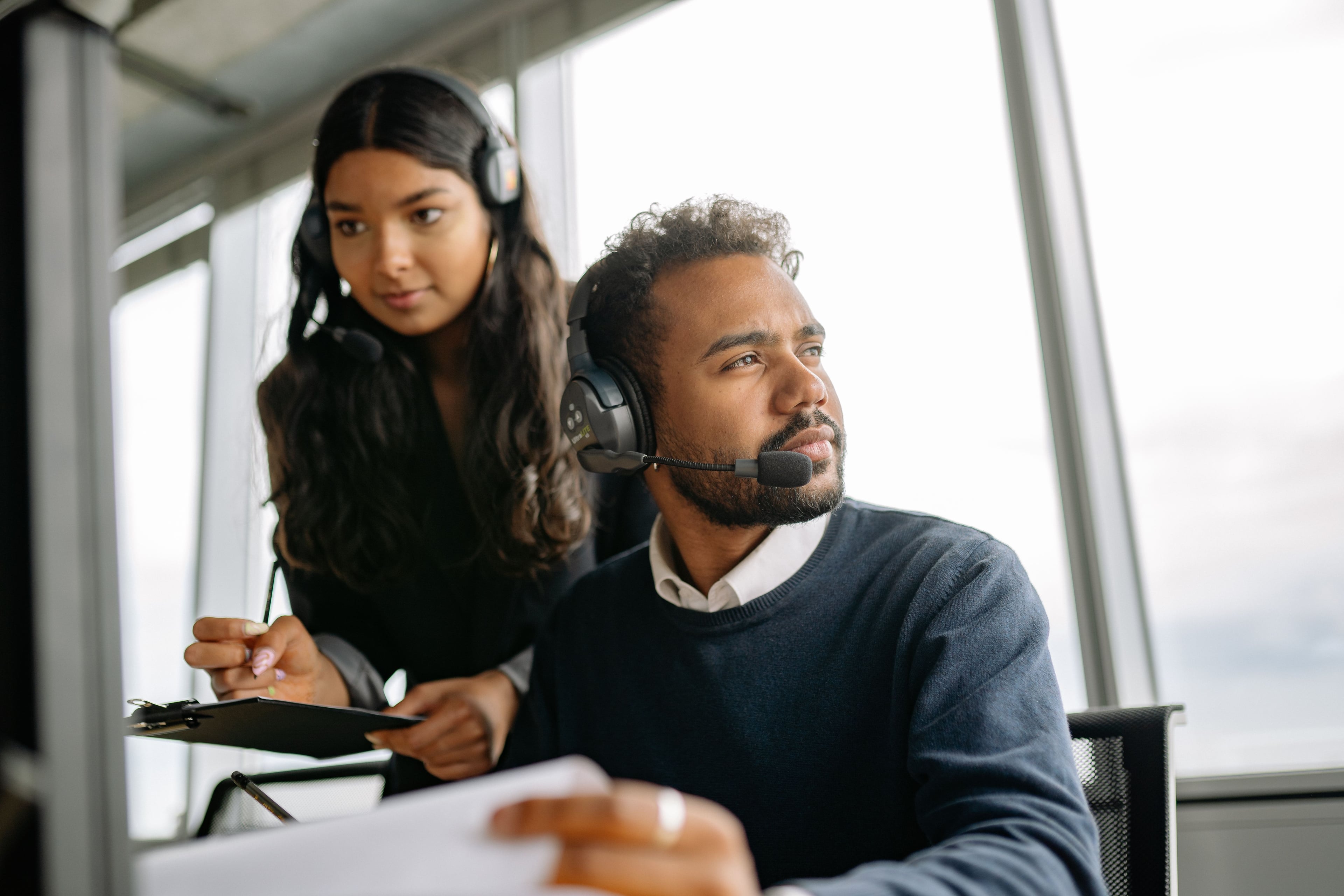 A colleague offering guidance to a teammate using a headset