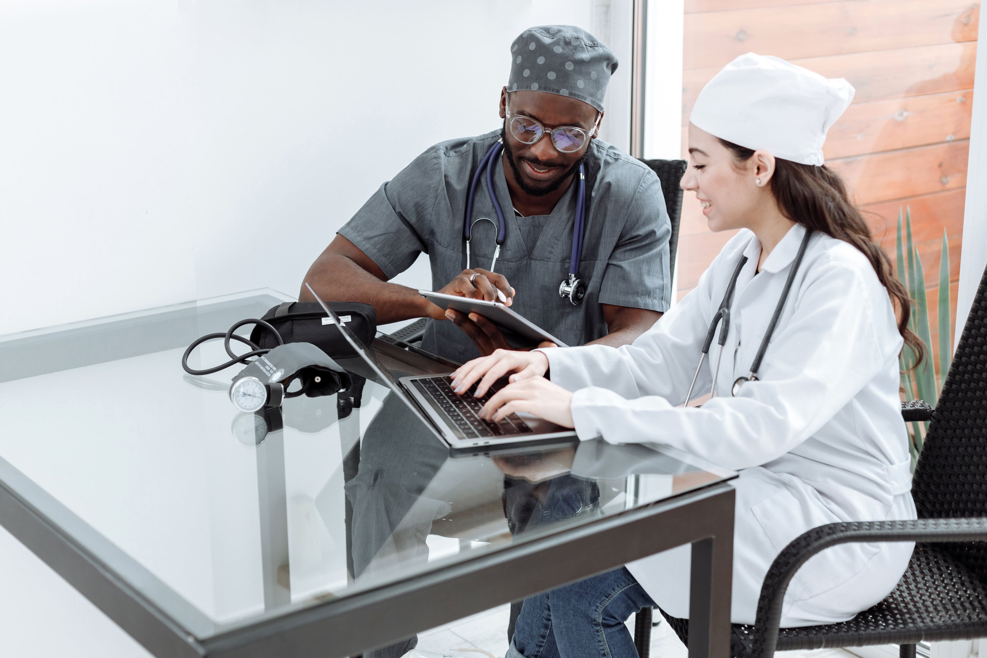 Healthcare colleagues working side by side with a tablet and laptop